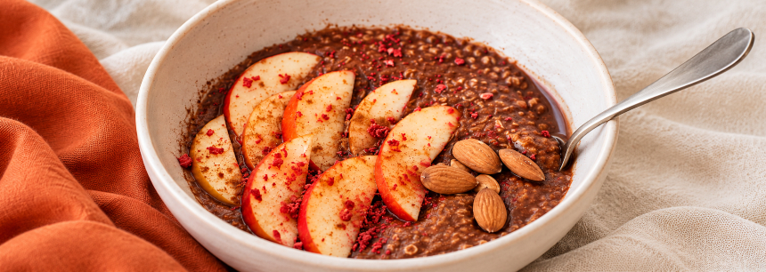 Nahaufnahme von Porridge mit Apfelscheiben, Mandeln und gefriergetrockneten Himbeeren